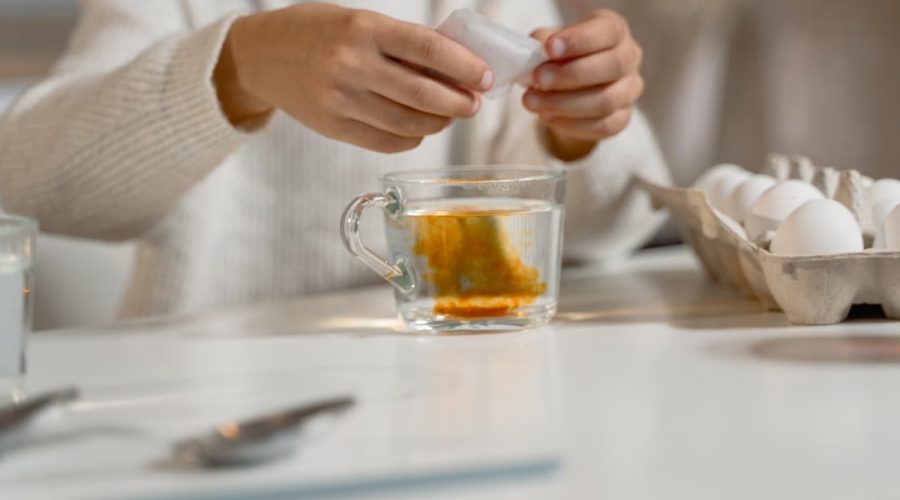 Close-up of hands dyeing eggs with natural colors, in a cozy indoor setting.